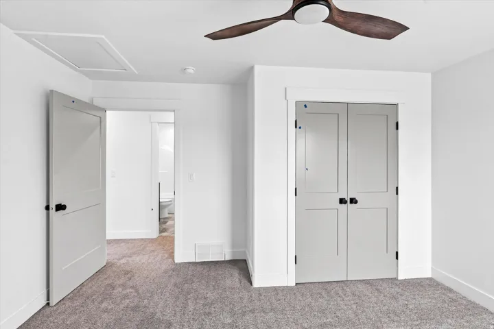 Ceiling fan with wood-finish blades, recessed lighting, and gray carpet flooring