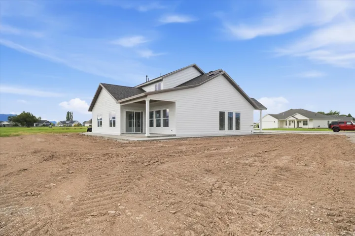 Rear exterior showcasing a covered patio with white columns, multiple large windows, and white horizontal siding