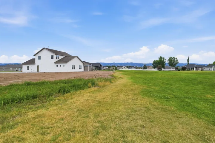 Expansive green space and a newly constructed white exterior home with a multi-gabled roofline