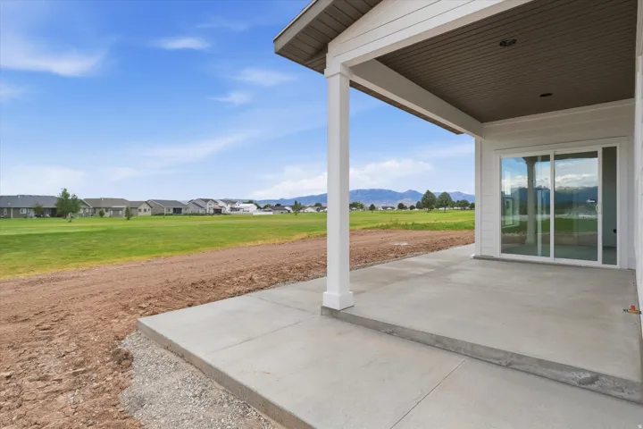 Covered patio with durable concrete flooring, white support columns, and a beadboard ceiling