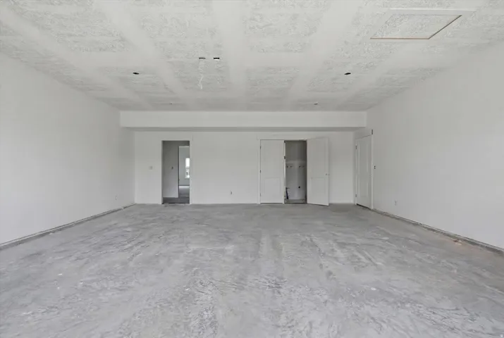 Spacious unfinished room with concrete flooring, white painted walls, and a textured ceiling