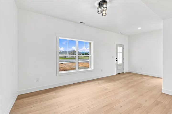 Wood-finish flooring, white trim, recessed lighting, and a multi-pane window