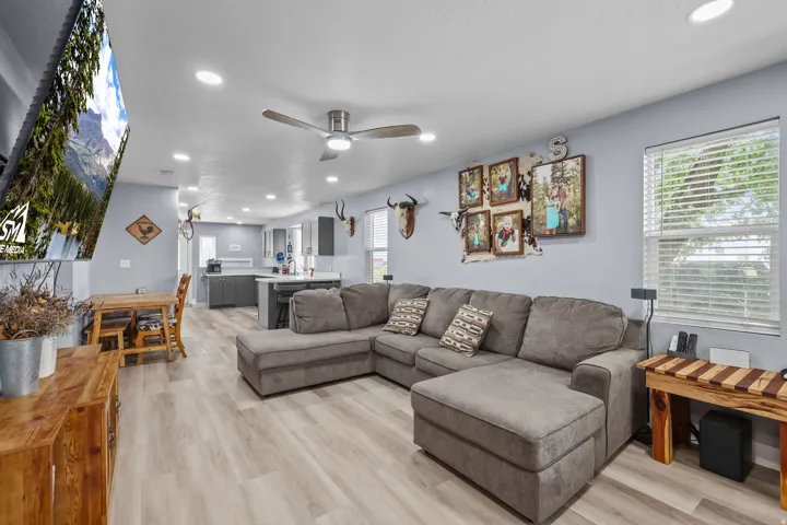 Open-concept living space featuring wood-finish flooring, recessed lighting, a ceiling fan, and a light gray wall color