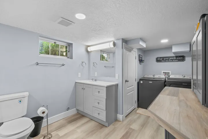 Bathroom featuring a single vanity with a white countertop and gray cabinetry, light wood-finish flooring, a window, and recessed lighting