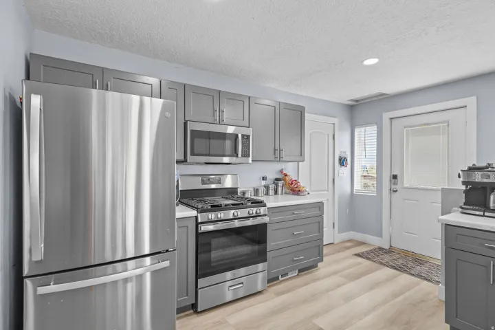 Kitchen featuring stainless steel appliances, grey cabinetry, light-toned wood-finish flooring, white countertops, and recessed lighting