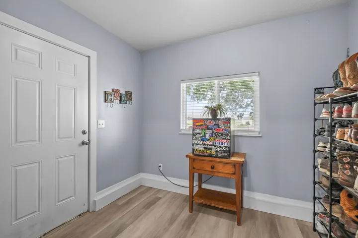 Entryway featuring a paneled door with polished hardware, wood-finish flooring, and light blue wall paint