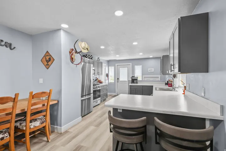 Modern kitchen featuring dark cabinetry, stainless steel appliances, light countertops, recessed lighting, and wood-finish flooring