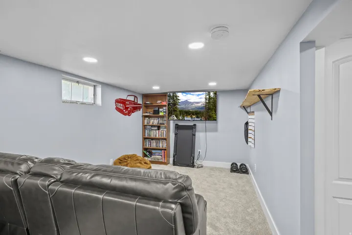 Lower-level entertainment space featuring recessed lighting, a built-in wood-finish bookshelf, and light gray wall paint