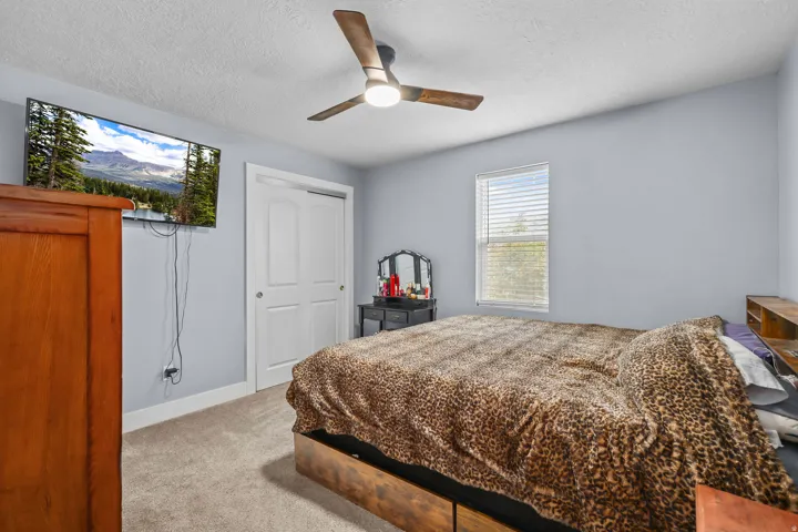 Carpeted room featuring a ceiling fan with integrated lighting, a window with blinds, and bi-fold closet doors