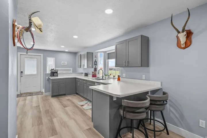 Kitchen featuring wood-finish flooring, gray cabinetry, white countertops, recessed lighting, and a breakfast bar