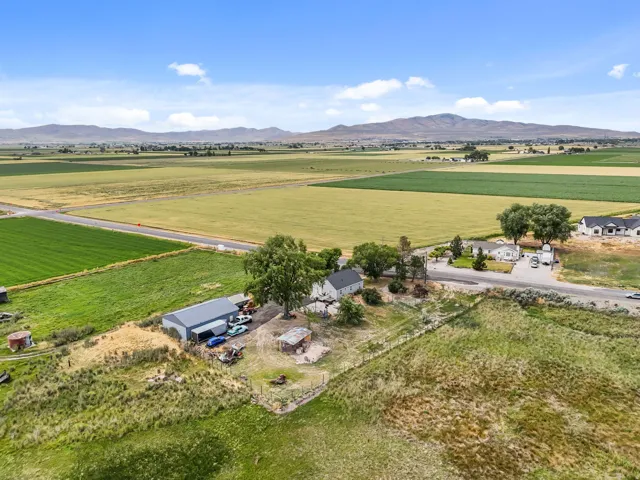 Expansive property featuring a single-story dwelling, a large detached utility building, and extensive open land