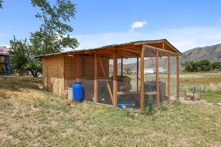 Wood-frame outbuilding with an attached screened enclosure, featuring a pitched roof and a gravel-like ground cover