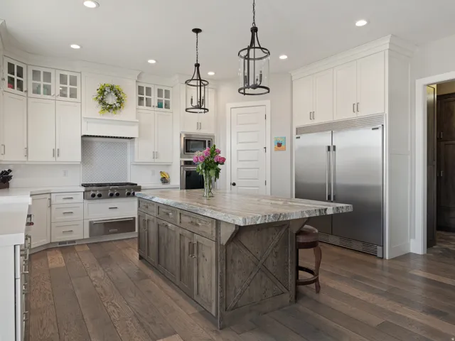 Gourmet kitchen featuring white cabinetry, stainless steel appliances, a range hood, and a large wood-finish island with a stone countertop