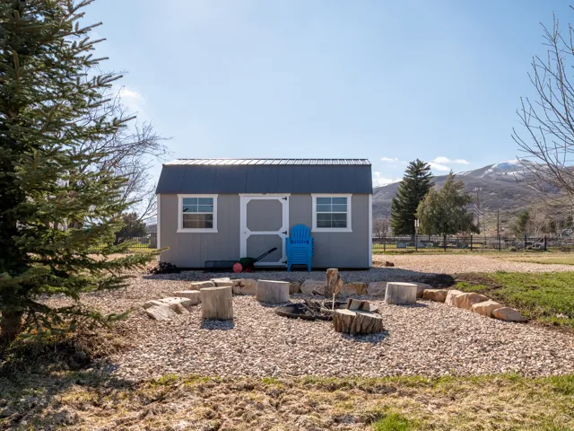 Detached storage shed featuring a corrugated metal roof and white-framed windows