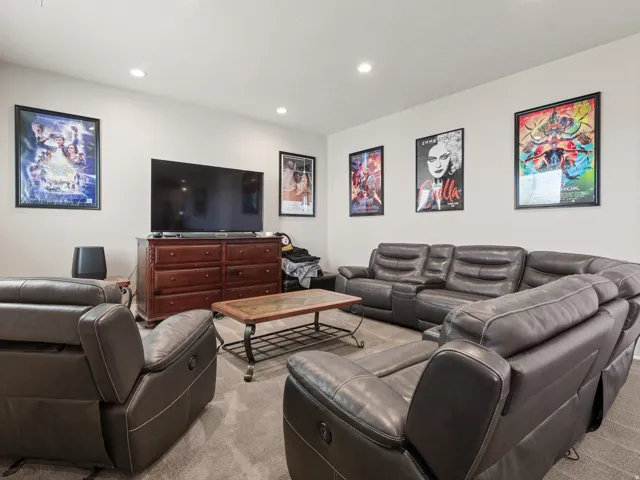 Recessed lighting illuminates the room, featuring light neutral-toned walls and dark gray carpet flooring