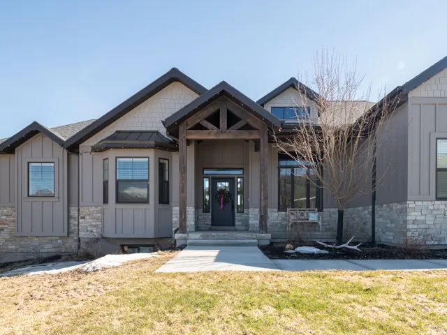 Craftsman-style exterior featuring a prominent timber-frame entry, board and batten siding, stone accents, dark-framed windows, and a bay window