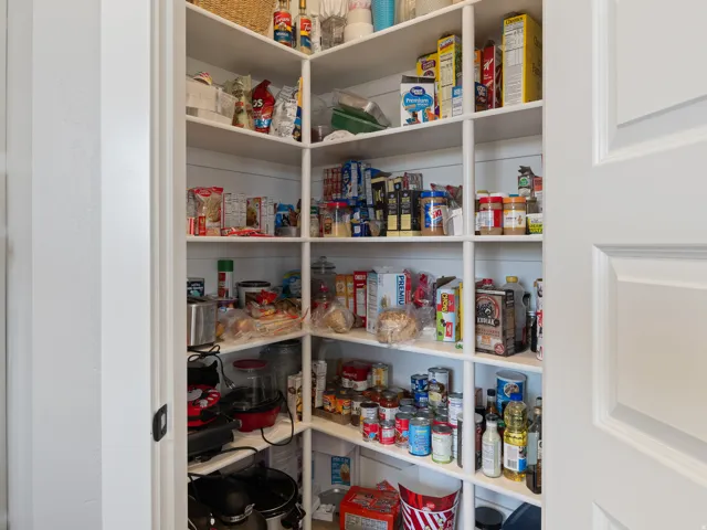 Expansive walk-in pantry featuring white shiplap walls and abundant built-in shelving for extensive storage