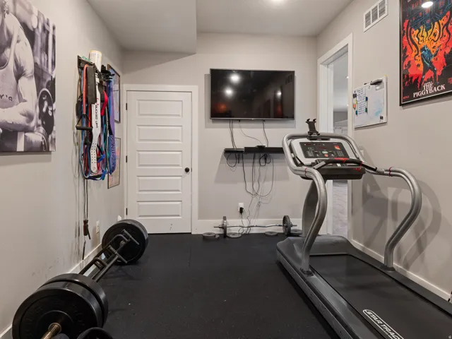 Dedicated fitness room with rubberized flooring, recessed lighting, and a wall-mounted television