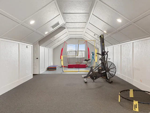 Attic space featuring sloped ceilings, recessed lighting, and integrated wall paneling