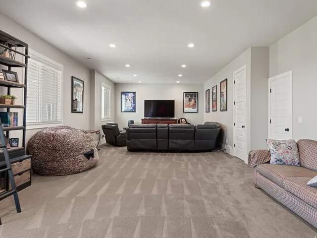 Spacious room featuring neutral carpeting, recessed lighting, and multiple windows with white blinds