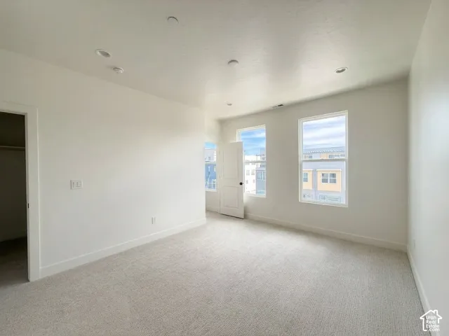 Light-toned carpeting, white walls, multiple windows, and recessed lighting