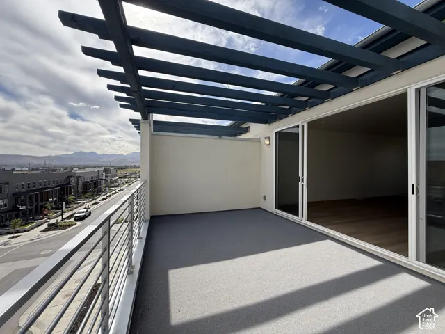 Terrace featuring a dark wood pergola, sliding glass doors, a grey textured floor, and a metal railing