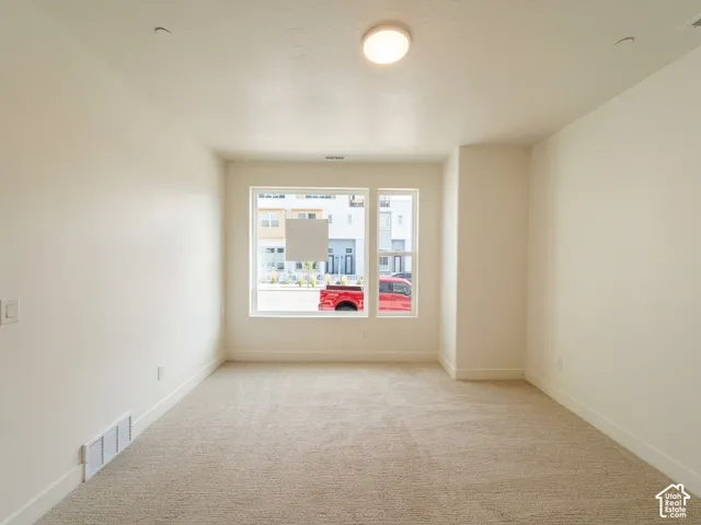 Carpeted room featuring a large window, neutral wall paint, and a flush-mount ceiling light fixture
