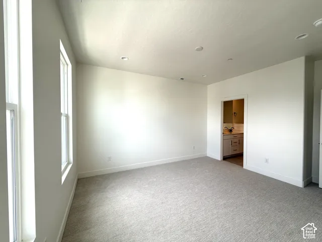 Spacious room featuring multiple windows, recessed lighting, neutral-toned carpet, and a white color palette