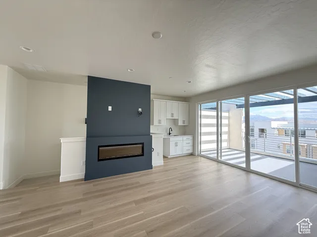 Recessed lighting, wood-finish flooring, built-in electric fireplace, sliding glass doors, and a wet bar with white cabinetry
