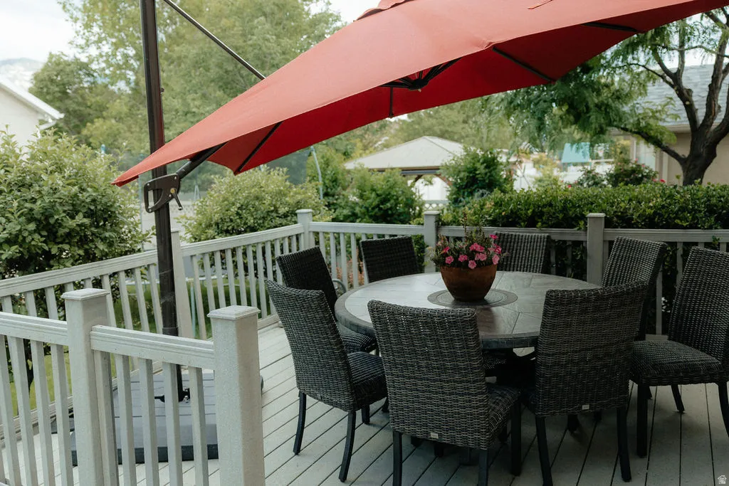 Spacious outdoor deck featuring light-toned decking, coordinating railing, and mature perimeter landscaping