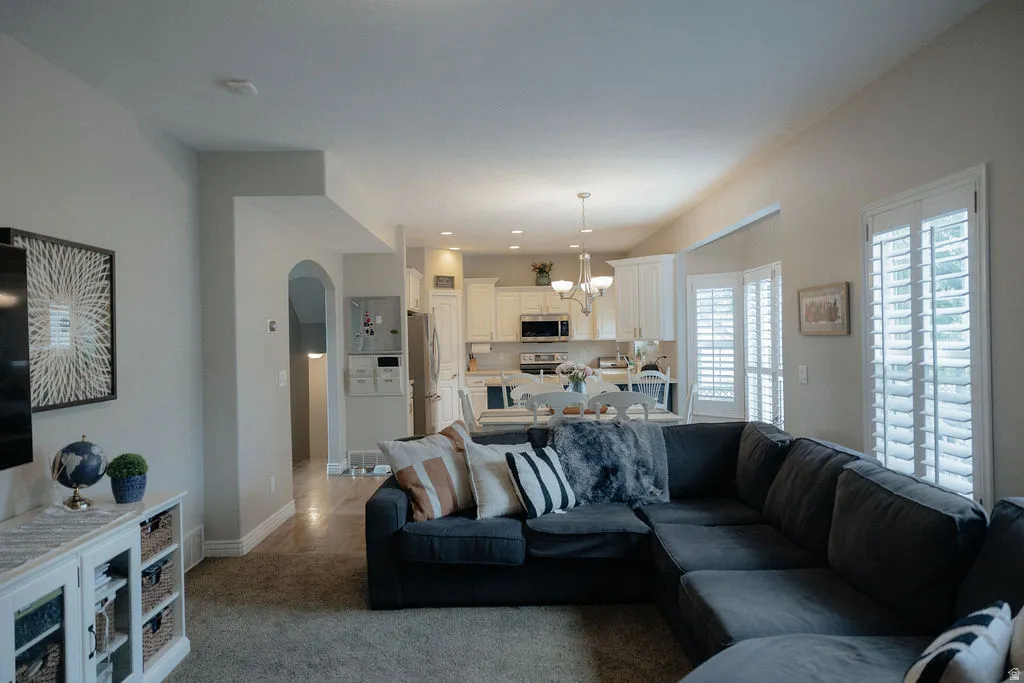 Living area featuring vaulted ceilings, plantation shutters, and an arched entryway