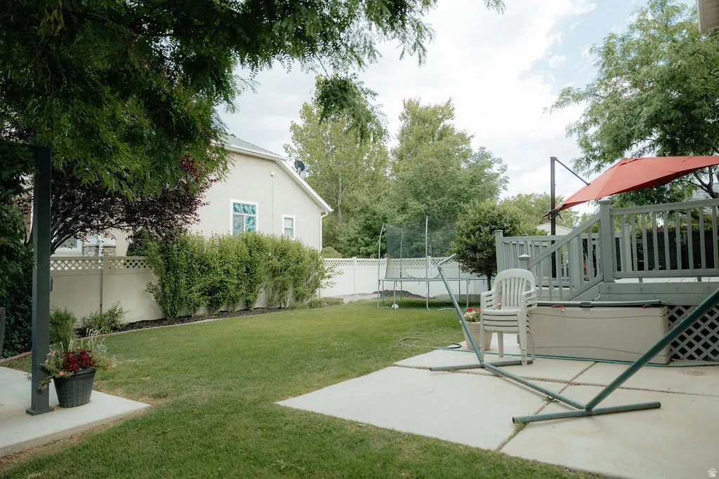 Expansive backyard featuring a lush lawn, concrete patio, and a multi-level deck with wood railing
