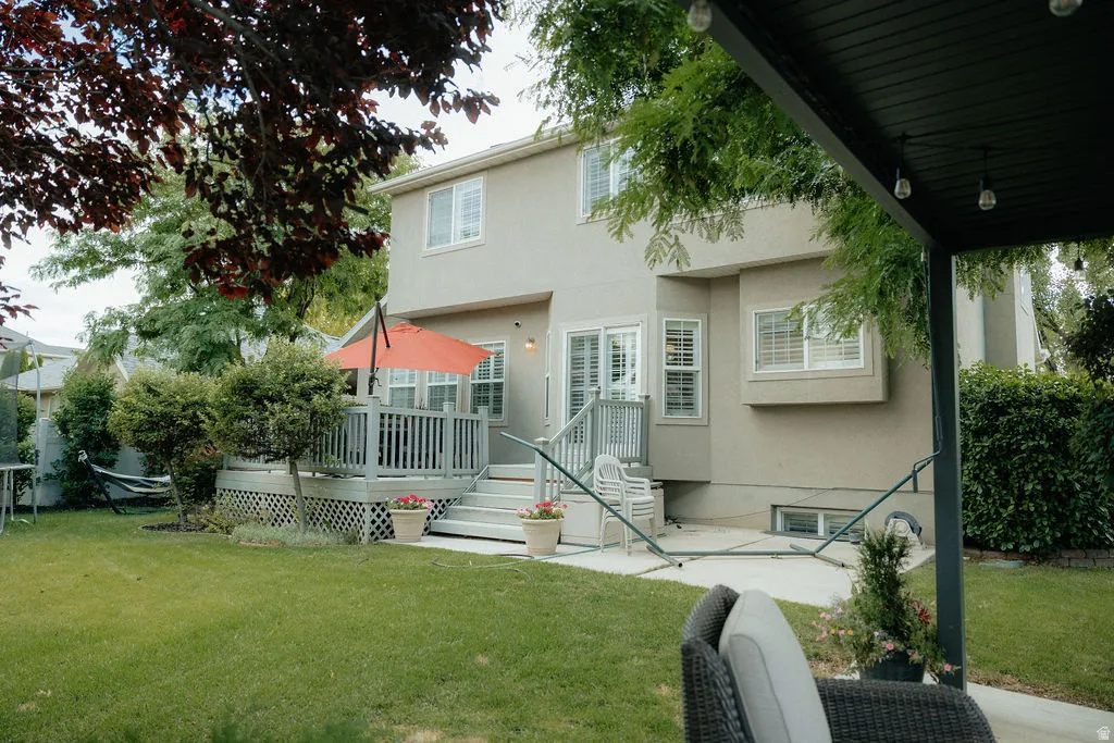 Rear stucco exterior featuring a wood-decked patio with lattice skirting and steps