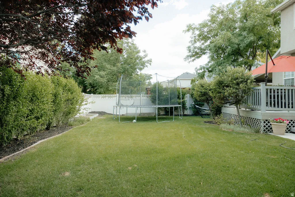 Spacious backyard featuring a manicured lawn, a white privacy fence, and mature perimeter trees
