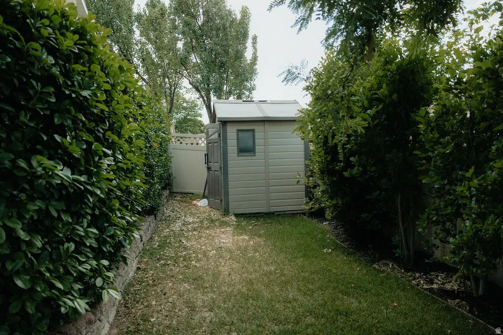 Backyard featuring a shed with a window, surrounded by mature perimeter foliage