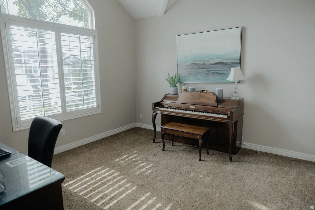 Vaulted ceilings accent a space featuring a large window with plantation shutters and an arched transom window
