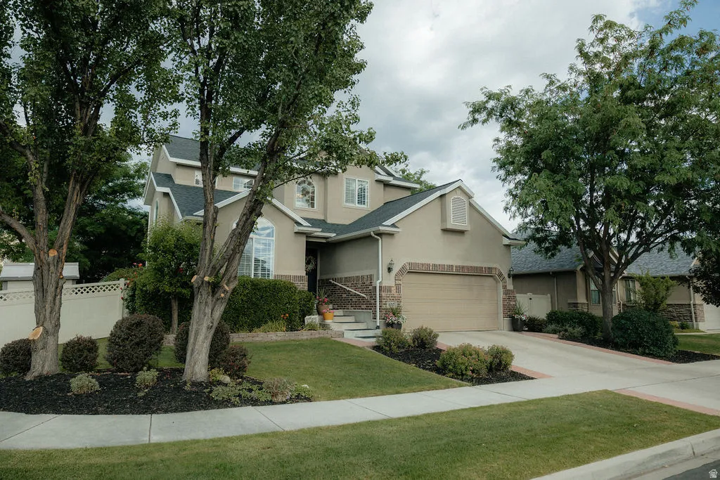 Stucco exterior residence featuring a two-car garage, stone accents, and a concrete driveway