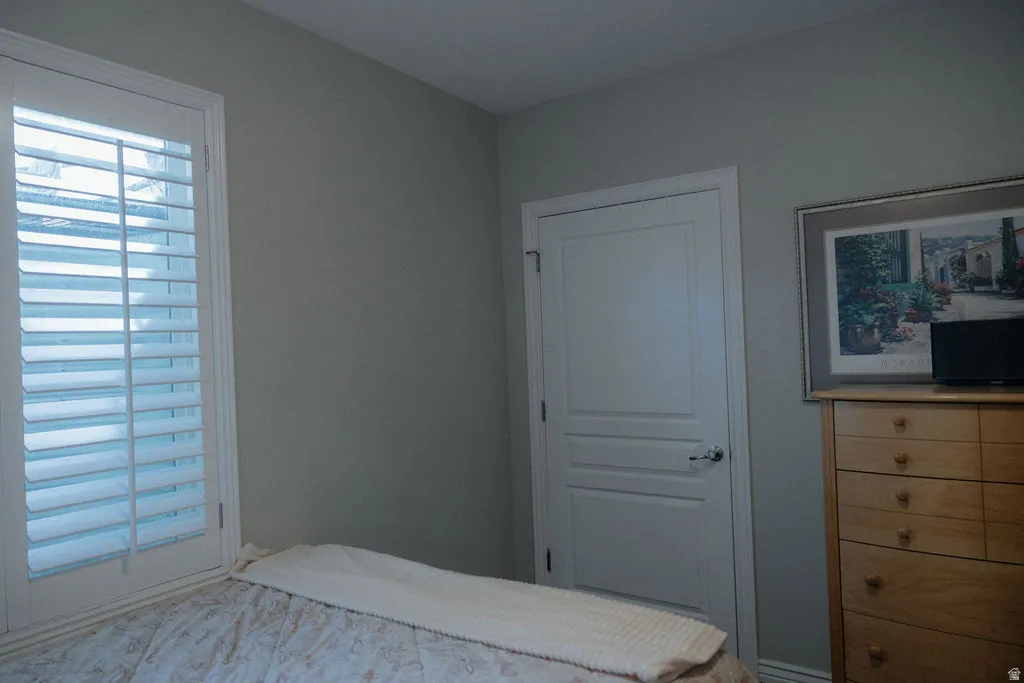 Room featuring neutral-toned walls, white interior door with panel detailing, and a window with white plantation shutters