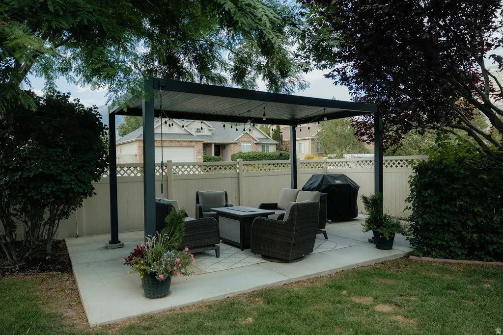 Outdoor entertaining area featuring a dark-framed pergola with string lighting, situated on a concrete patio