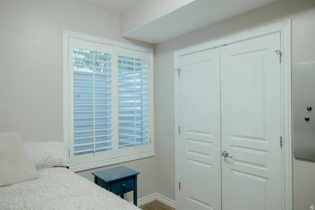 Room featuring a window with white louvered shutters and white trim, paired with white paneled bifold doors