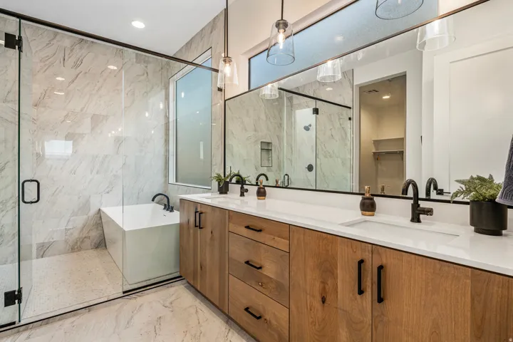 Contemporary bathroom featuring a dual vanity with light wood-finish cabinetry and black hardware