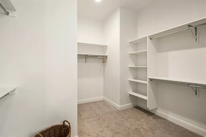 Expansive walk-in closet featuring built-in shelving, multiple hanging rods, and recessed lighting