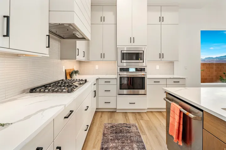 Modern kitchen featuring light cabinetry, stainless steel appliances, a gas range, white countertops, and wood-finish flooring