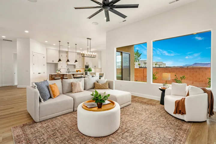 Open-concept living area featuring high ceilings with a modern ceiling fan, large picture windows, wood-finish flooring, and recessed lighting