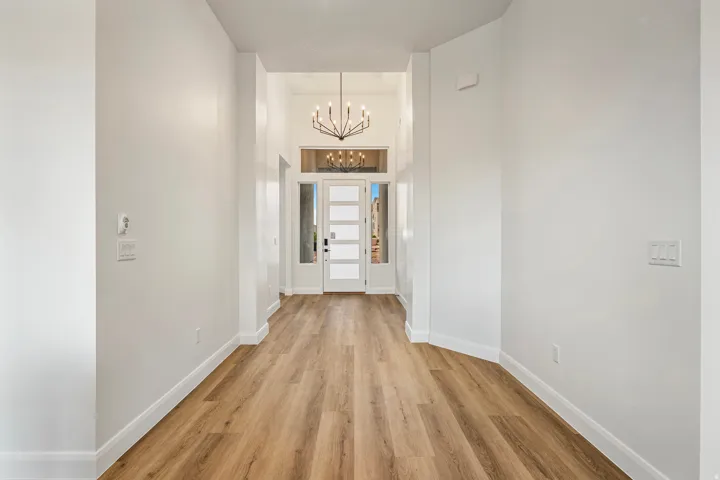 Entryway featuring wood-finish flooring, a modern chandelier, a transom window, and white interior walls