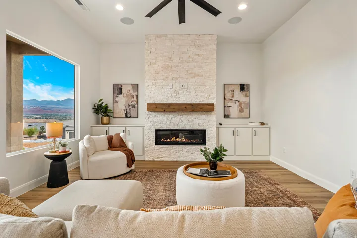 Living area featuring a floor-to-ceiling stone fireplace with a wood mantle, built-in cabinetry, and wood-finish flooring