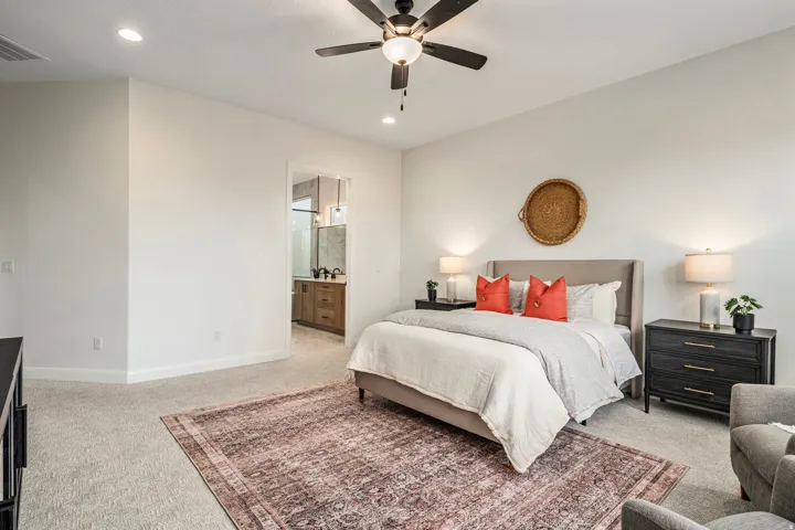 Spacious carpeted room featuring a ceiling fan with integrated lighting, recessed lighting, and a doorway revealing a bathroom with a dual vanity