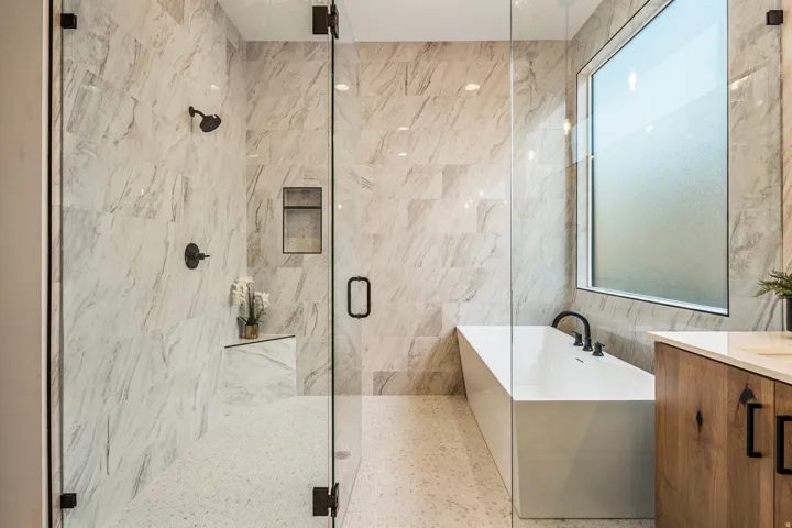 Contemporary bathroom featuring a spacious walk-in shower with a built-in niche and bench, a modern freestanding soaking tub, and a wood-finish vanity with a light-toned countertop