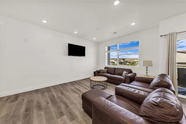 Living area featuring wood-finish flooring, recessed lighting, and white baseboards