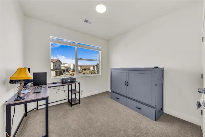 Neutral wall paint with carpeted flooring, a large window, a built-in wall unit, and a ceiling-mounted light fixture